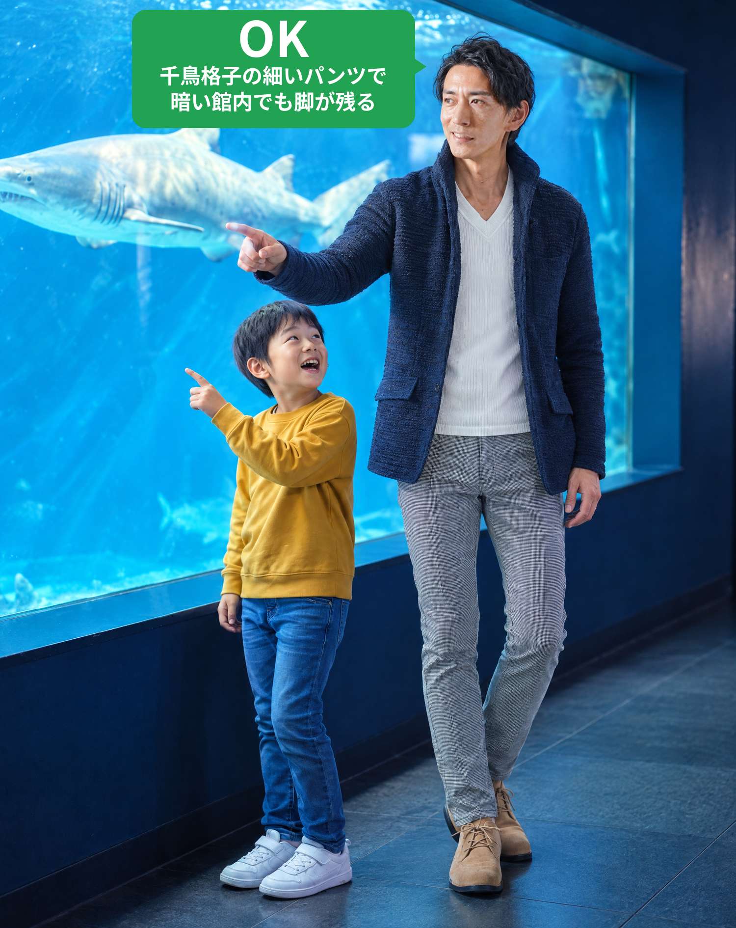 OKコーデ　水族館のサメの水槽の前で、パパと子供が一緒にサメを指さして笑顔で楽しむシーン（OKマーク付き）