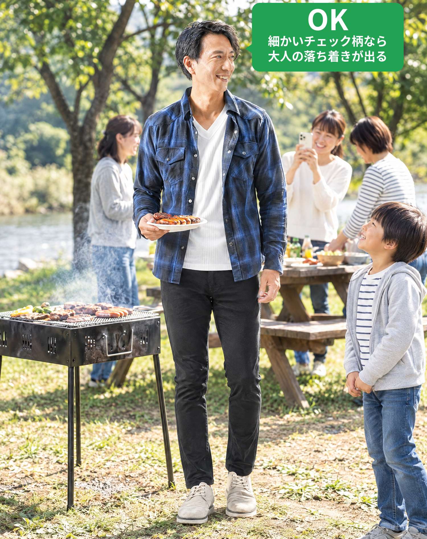 OKコーデ　河原のバーベキュー場で、焼きたてのソーセージを手に子供に見上げられ、ママにスマホで撮られるシーン（OKマーク付き）