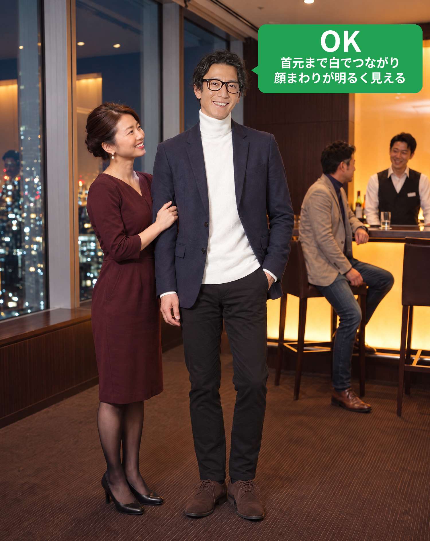 OKコーデ　夜景の見えるホテルのバーで、笑顔の奥さんと腕を組んで並ぶシーン（OKマーク付き）