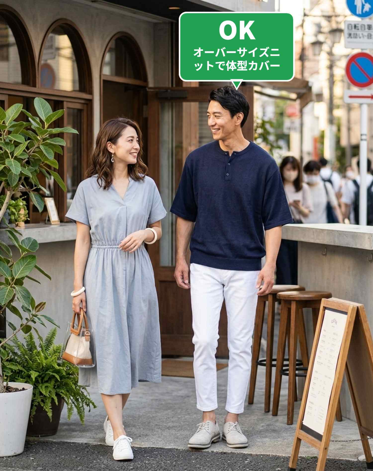 OKコーデ　待ち合わせ場所でのネイビー接触冷感オーバーサイズサマーニットと白スキニーテーパードアンクルチノパンツの立ち姿シチュエーション（OKマーク付き）
