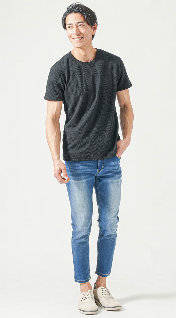黒の柄入りクルーネックTシャツに淡いウォッシュデニムと白のレザーシューズを合わせた、涼しげで垢抜けた印象の夏のメンズコーディネート