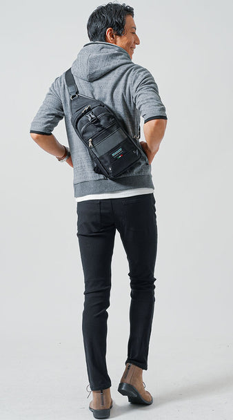 グレーパーカーと黒スキニーパンツに黒ボディバッグを合わせた大人のカジュアルコーデの後ろ姿