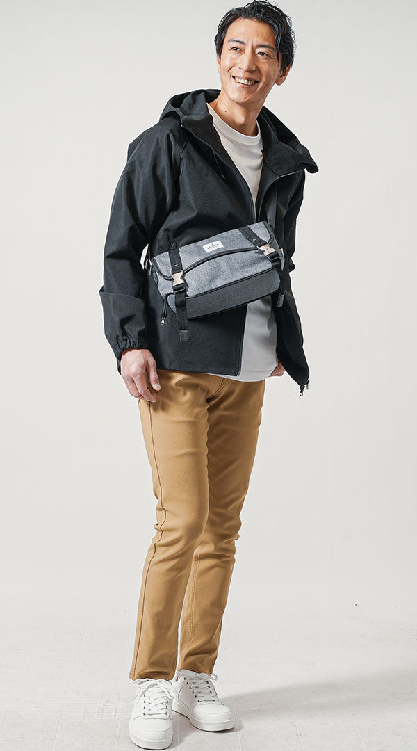 防水設計の黒マウンテンパーカーと白の防水スニーカーを取り入れた、キャメルパンツの雨の日メンズコーデ