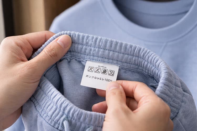 スウェットセットアップの洗濯表示を確認している様子