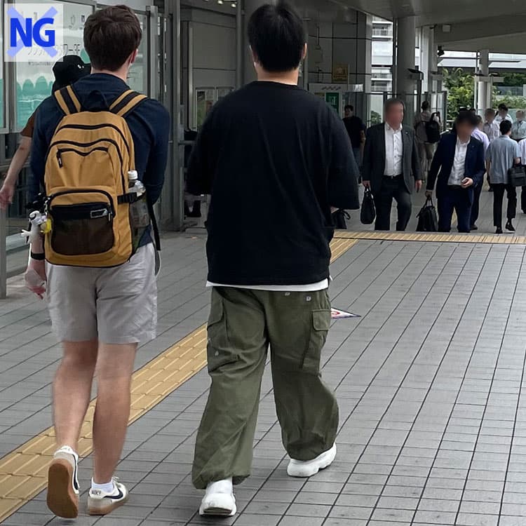 街中のどこかおじさん臭い白Tシャツと黒パンツのコーデをした男性