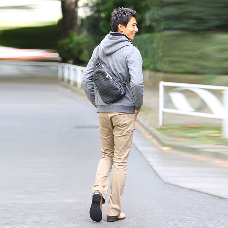 40代メンズが街歩きで着こなすグレーパーカと編み込みデザイン黒ボディバッグのカジュアルコーディネート